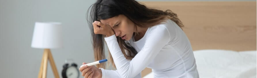 Young woman sit on bed at home feel broken depressed with negative pregnancy test results